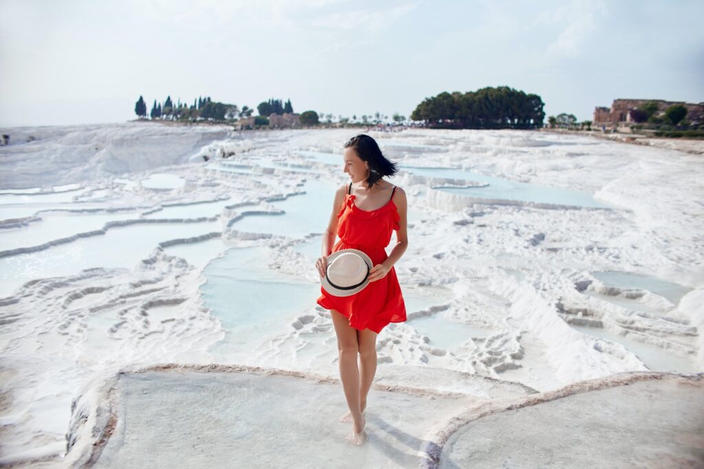 Girl in red dress on white travertines, Pamukkale